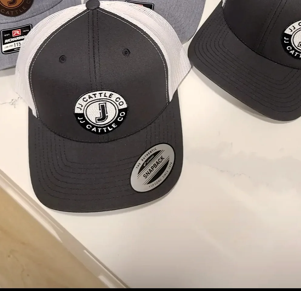 JJ Cattle Co. branded snapback hats — JJ leather patch on dark grey trucker style